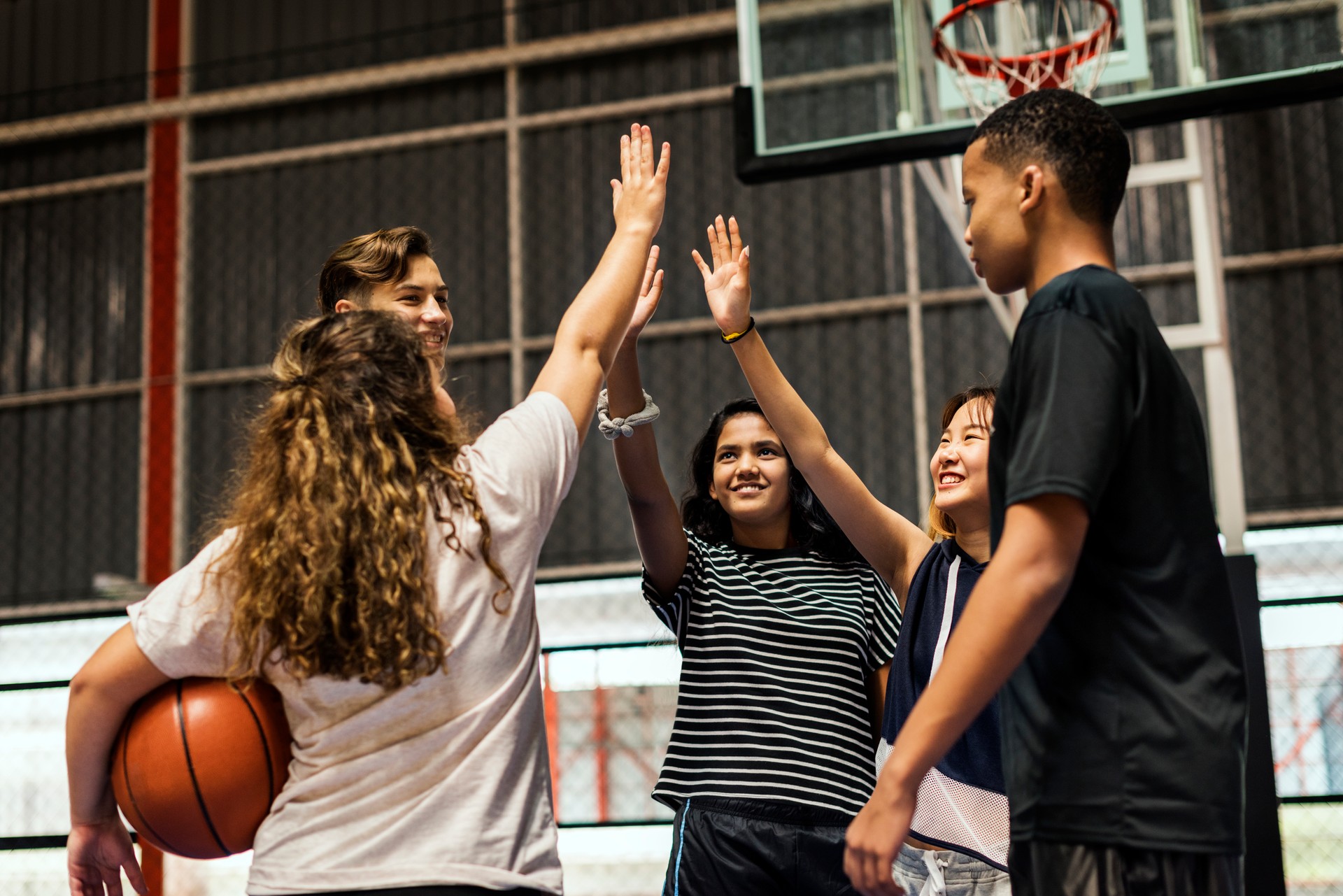 Group of teenager friends on a basketball court giving each other a high five